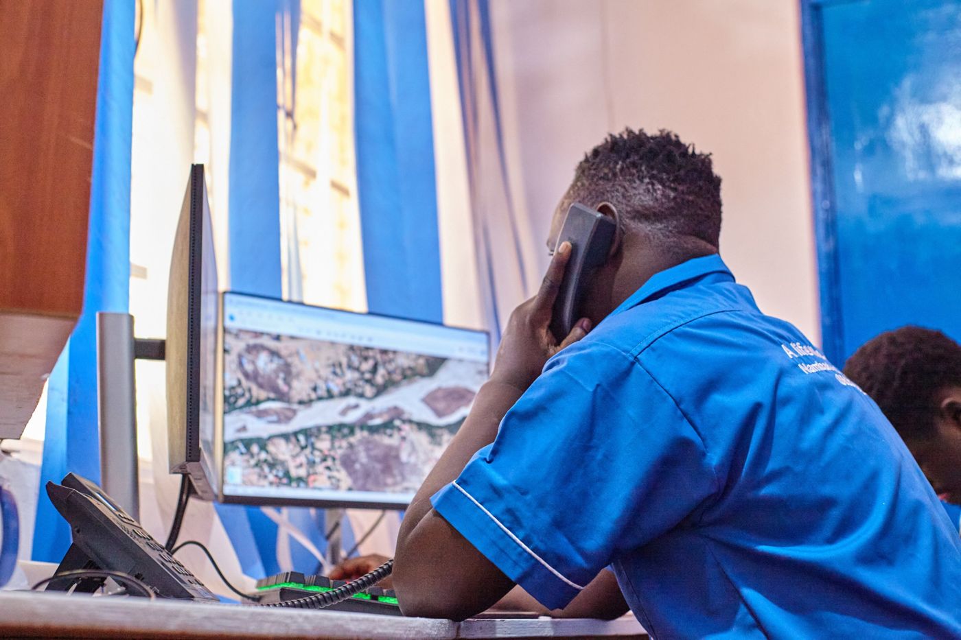 A call centre officer taking a call with a map on screen